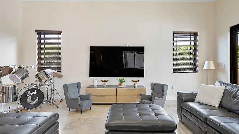 Real MLS listing photo: the family room media wall with a mounted TV and a drum kit