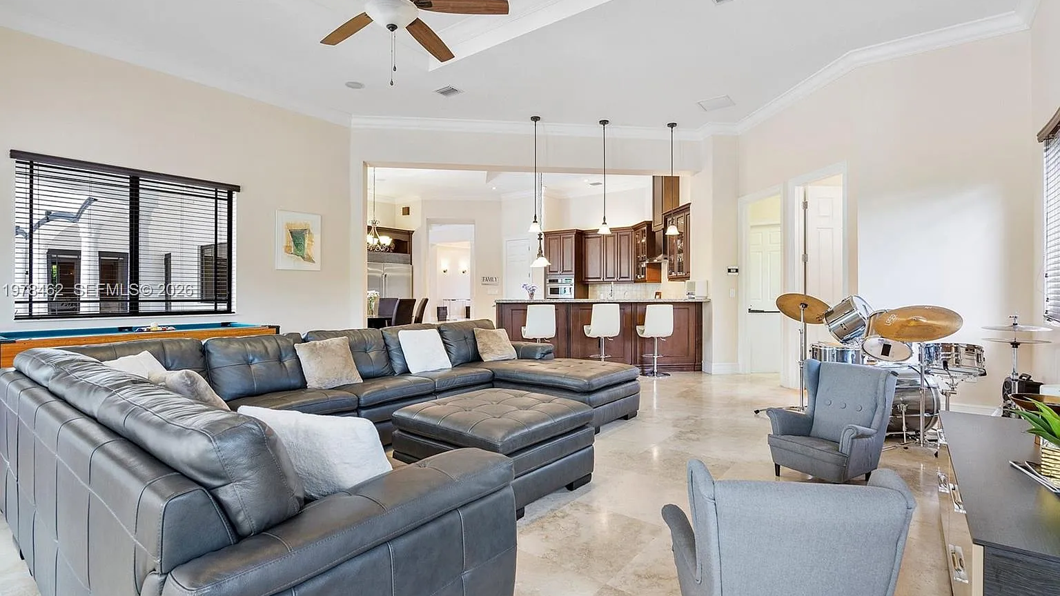 Real MLS listing photo: the family room's grey leather sectional with the open kitchen bar behind